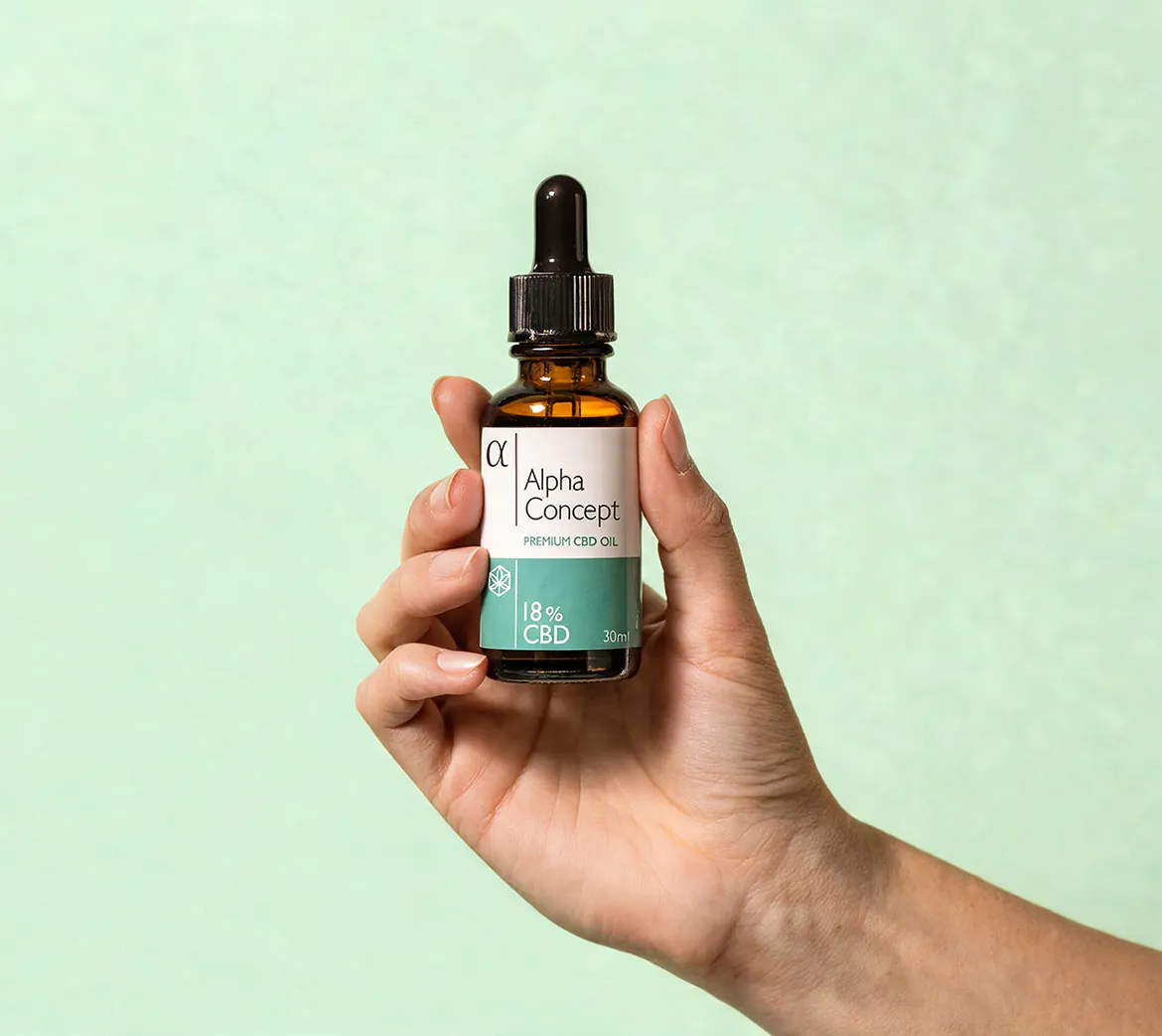 Ruka drži bočicu Alpha Concept CBD ulja 18% na mint zelenoj pozadini